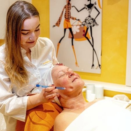 JetPeel Behandlung - Eine Frau die eine liegende Kundin behandelt